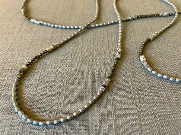 closeup of gemstone bead necklace comprising black and white feldspar, silver hematite and dark grey pyrite