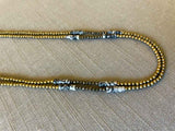 side view of gemstone bead necklace comprising black and white network agate, light gold hematite and dark grey pyrite