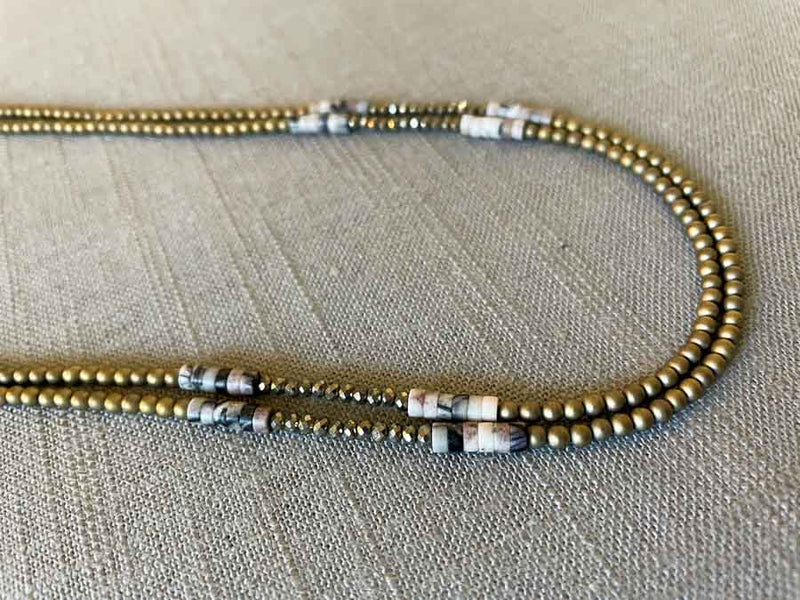 side view of gemstone bead necklace comprising black/white/nude feldspar, light gold hematite and golden pyrite