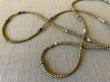 closeup of gemstone bead necklace comprising black/white/nude feldspar, light gold hematite and golden pyrite