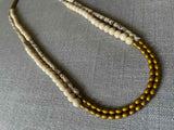  top view of gemstone bead necklace comprising black and cream feldspar, off-white fossil jasper and gold hematite