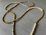 closeup of gemstone bead necklace comprising black and cream feldspar, off-white fossil jasper and gold hematite