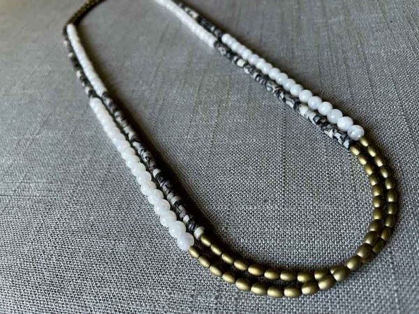 top view of gemstone bead necklace comprising black and white feldspar, white moonstone and light gold hematite