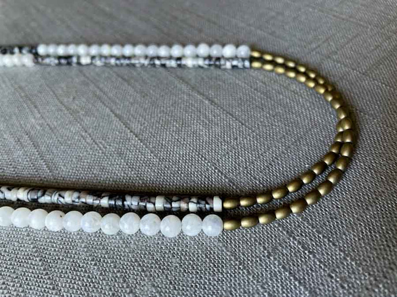 side view of gemstone bead necklace comprising black and white feldspar, white moonstone and light gold hematite