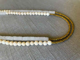 side view of gemstone bead necklace comprising white moonstone , off-white fossil jasper and gold hematite