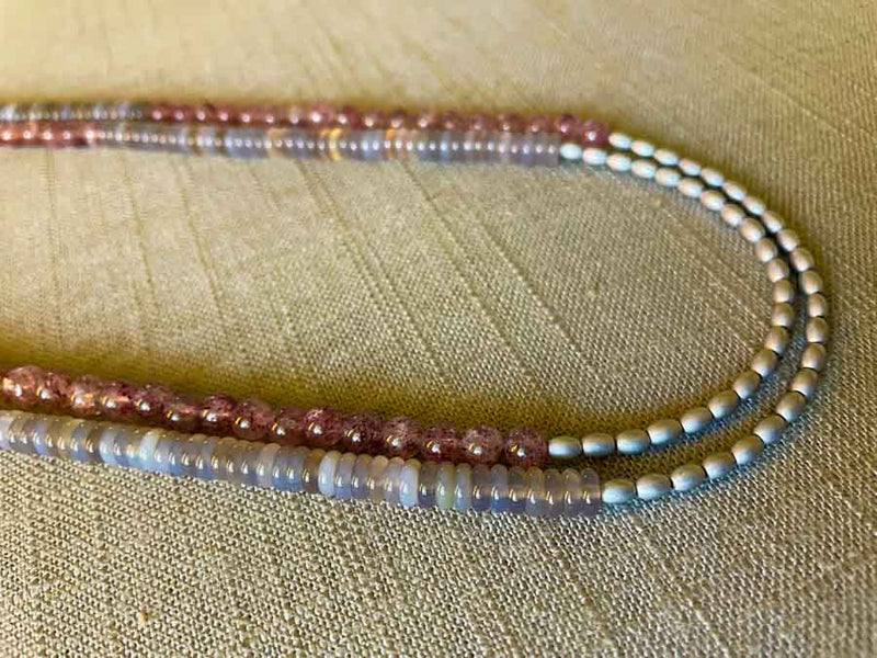 side view of gemstone bead necklace comprising grey moonstone , pink strawberry quartz and silver hematite