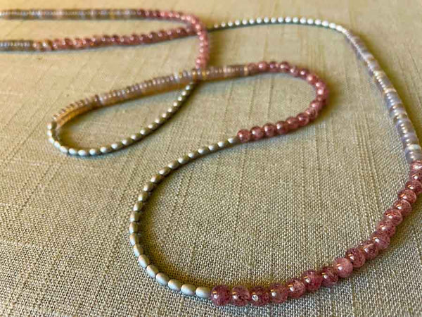 closeup of gemstone bead necklace comprising grey moonstone , pink strawberry quartz and silver hematite