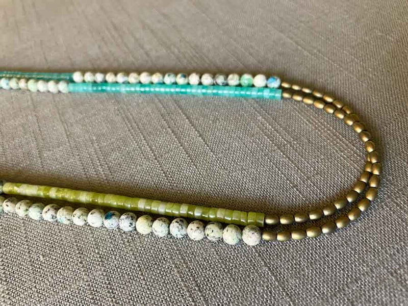 side view of gemstone bead necklace comprising white k2 granite, green jade, blue amazonite and light gold hematite