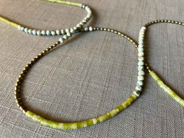 closeup of gemstone bead necklace comprising white speckled k2 granite, green jade and light gold hematite