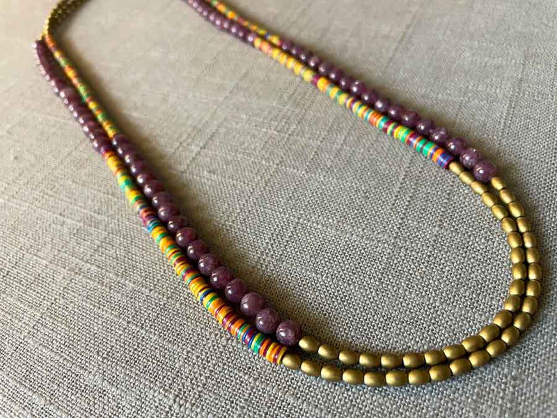 top view of gemstone bead necklace comprising multicolored vinyl discs, purple lepidolite and gold hematite