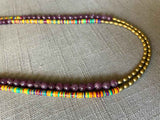 side view of gemstone bead necklace comprising multicolored vinyl discs, purple lepidolite and gold hematite