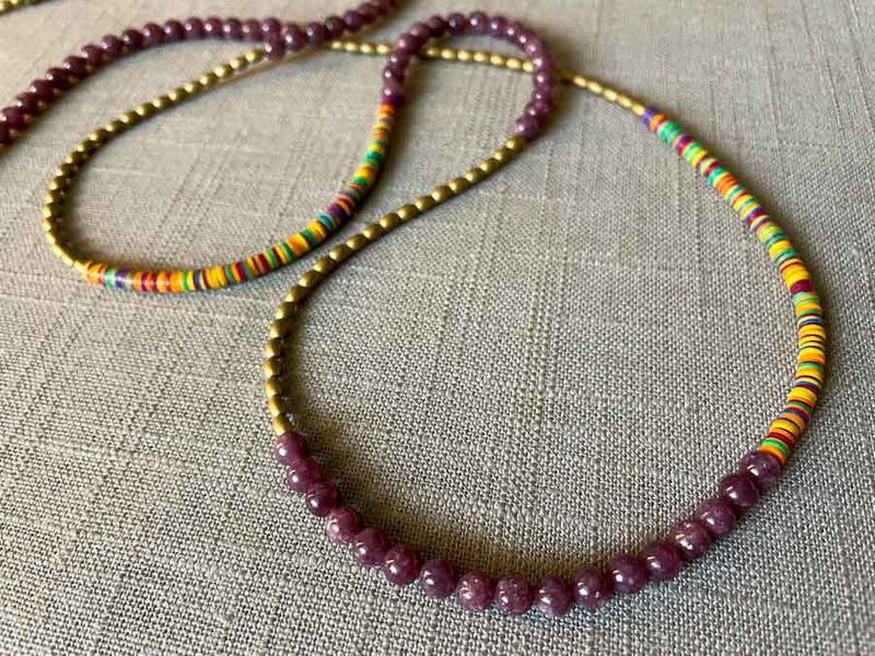 closeup of gemstone bead necklace comprising multicolored vinyl discs, purple lepidolite and gold hematite