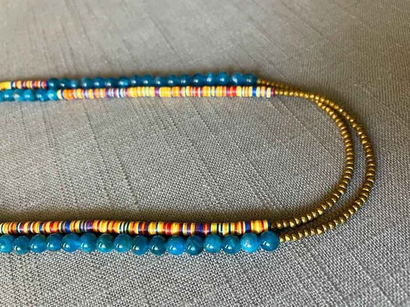 side view of gemstone bead necklace comprising multicolored vinyl discs, blue apatite and gold hematite