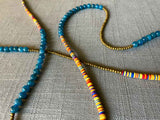 closeup of gemstone bead necklace comprising multicolored vinyl discs, blue apatite and gold hematite