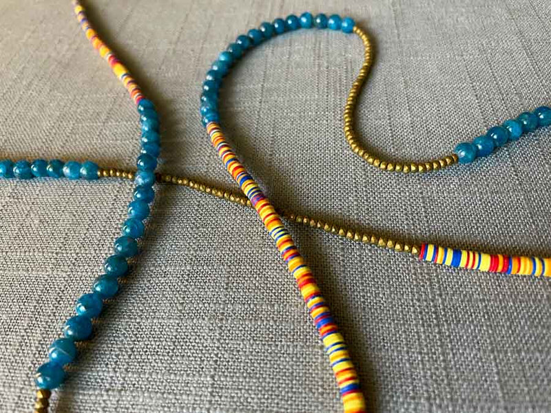 closeup of gemstone bead necklace comprising multicolored vinyl discs, blue apatite and gold hematite