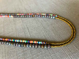 side view of gemstone bead necklace comprising multicolored vinyl discs, ruby blue kyanite and gold hematite