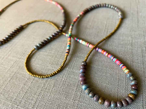 closeup of gemstone bead necklace comprising multicolored vinyl discs, ruby blue kyanite and gold hematite