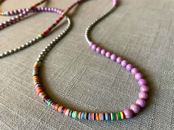 closeup of gemstone bead necklace comprising multicolored vinyl discs, light purple phosphosiderite and silver hematite