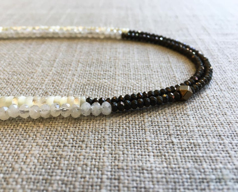 side view of gemstone bead necklace comprising white mother of pearl, dark grey pyrite and rainbow moonstone