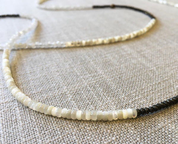 closeup of gemstone bead necklace comprising white mother of pearl, dark grey pyrite and rainbow moonstone