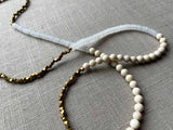 closeup of gemstone bead necklace comprising white moonstone, beige fossil jasper and bronze