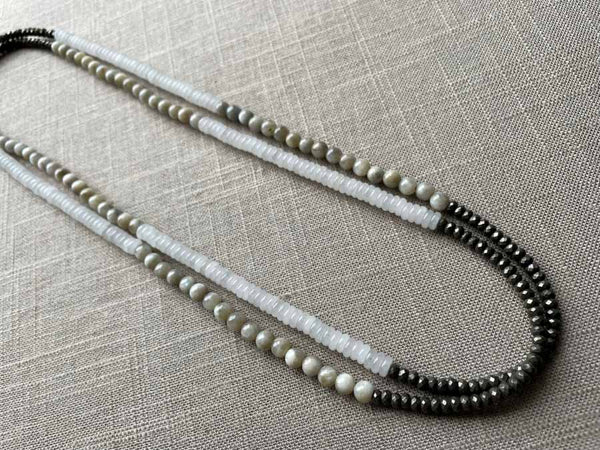 top view of gemstone bead necklace comprising white moonstone, off-white moonstone and dark grey pyrite