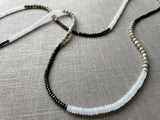 closeup of gemstone bead necklace comprising white moonstone, off-white moonstone and dark grey pyrite