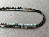 side view of gemstone bead necklace comprising blue chrysoprase, neutral strawberry quartz and dark grey pyrite