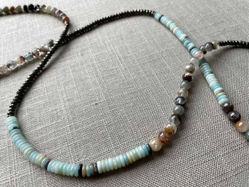 closeup of gemstone bead necklace comprising blue chrysoprase, neutral strawberry quartz and dark grey pyrite