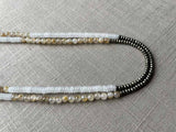 side view of gemstone bead necklace comprising white moonstone, neutral rutilated quartz and dark grey pyrite