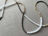 closeup of gemstone bead necklace comprising white moonstone, neutral rutilated quartz and dark grey pyrite