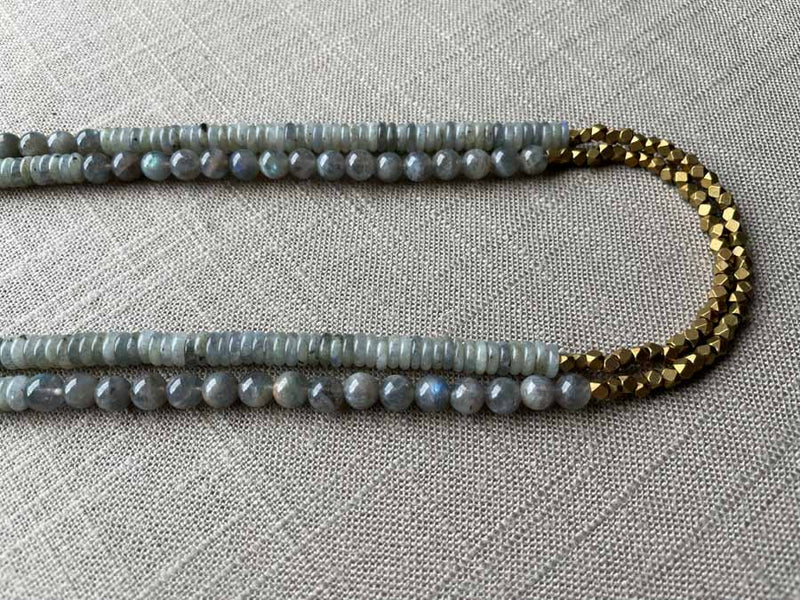 side view of gemstone bead necklace comprising grey moonstone, blue labradorite and bronze