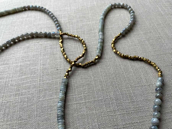 closeup of gemstone bead necklace comprising grey moonstone, blue labradorite and bronze