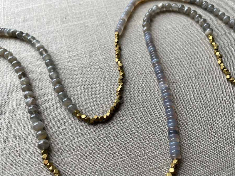 closeup of gemstone bead necklace comprising grey moonstone, purple smoky quartz and bronze