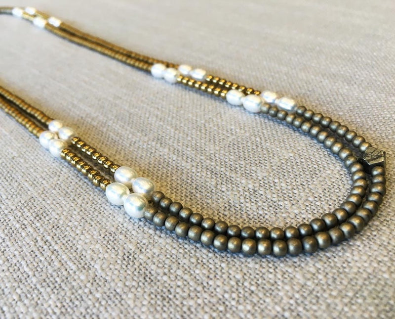 top view of gemstone bead necklace comprising white pearl, gold hematite and light gold hematite