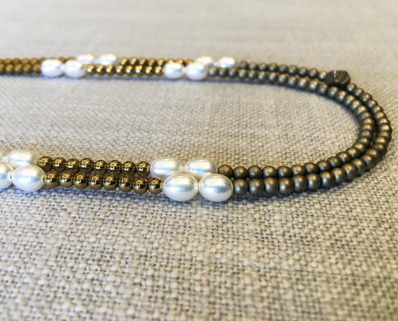 side view of gemstone bead necklace comprising white pearl, matte gold and matte light gold