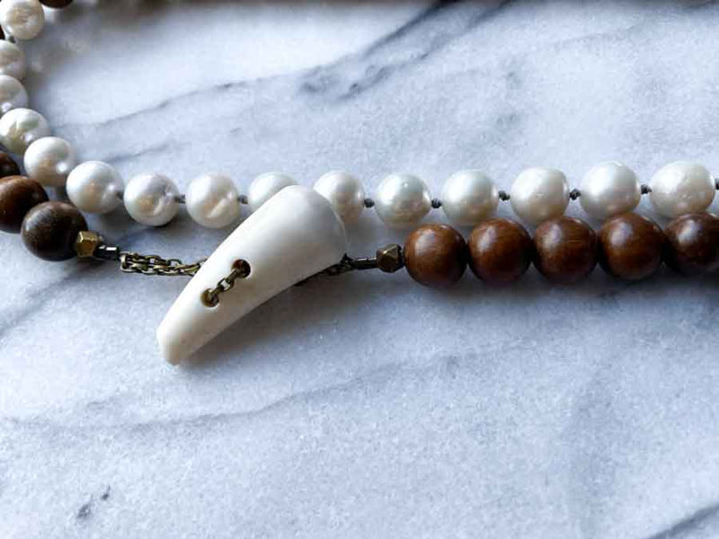 closeup of gemstone bead necklace comprising white pearl, neutral rutilated quartz and exotic wood with antler clasp