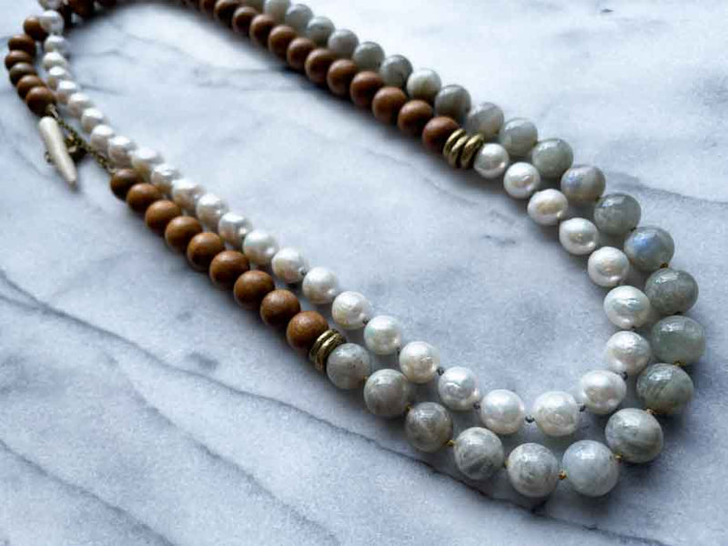 top view of gemstone bead necklace comprising white pearl, grey moonstone and exotic wood with antler clasp