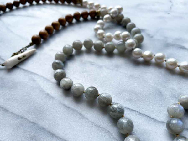 closeup of gemstone bead necklace comprising white pearl, grey moonstone and exotic wood with antler clasp