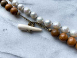 closeup of gemstone bead necklace comprising white pearl, grey moonstone and exotic wood with antler clasp