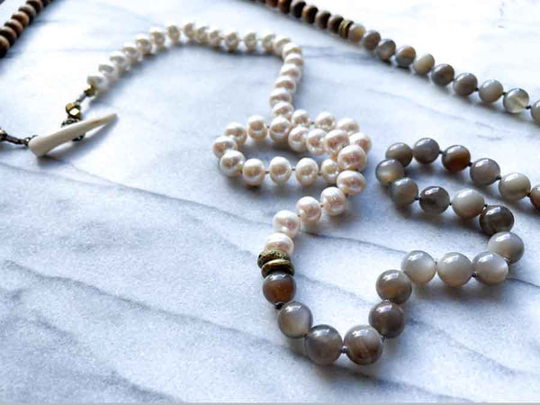 closeup of gemstone bead necklace comprising white pearl, grey mink moonstone and exotic wood with antler clasp