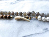 closeup of gemstone bead necklace comprising white pearl, grey mink moonstone and exotic wood with antler clasp