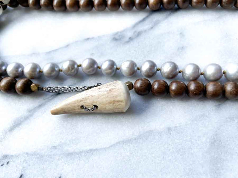 closeup of gemstone bead necklace comprising grey pearl, tourmalated quartz and exotic wood with antler clasp