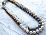 top view of gemstone bead necklace comprising white pearl, grey landscape jasper, natural quartz and exotic wood with antler clasp