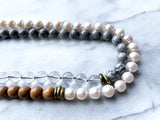 side view of gemstone bead necklace comprising white pearl, grey landscape jasper, natural quartz and exotic wood with antler clasp