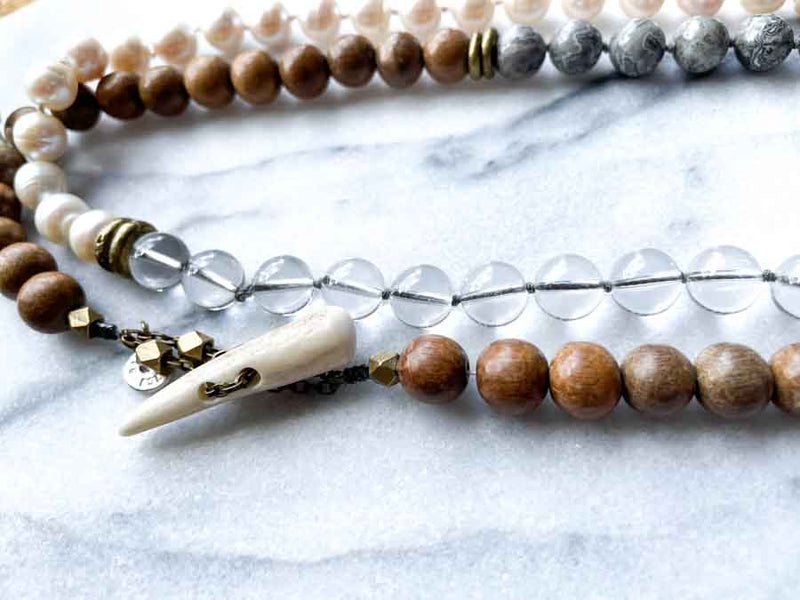 closeup of gemstone bead necklace comprising white pearl, grey landscape jasper, natural quartz and exotic wood with antler clasp