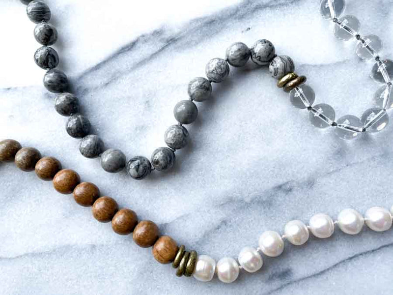 closeup of gemstone bead necklace comprising white pearl, grey landscape jasper, natural quartz and exotic wood with antler clasp