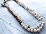 top view of gemstone bead necklace comprising white pearl, white bone, natural quartz and exotic wood with antler clasp