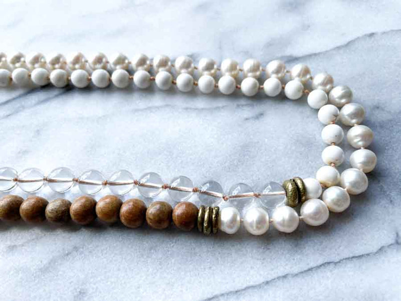 side view of gemstone bead necklace comprising white pearl, white bone, natural quartz and exotic wood with antler clasp