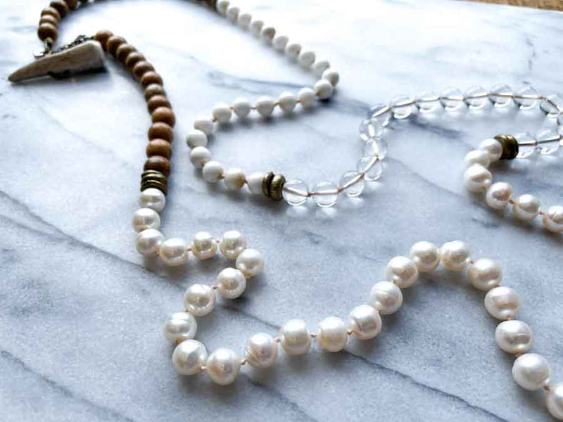 closeup of gemstone bead necklace comprising white pearl, white bone, natural quartz and exotic wood with antler clasp